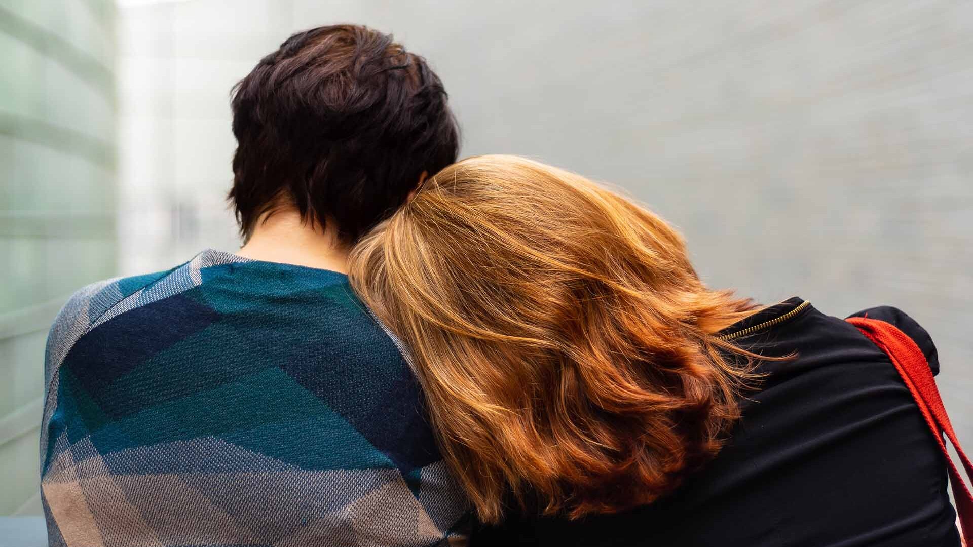 couple pictured from behind sitting on bench in an alley