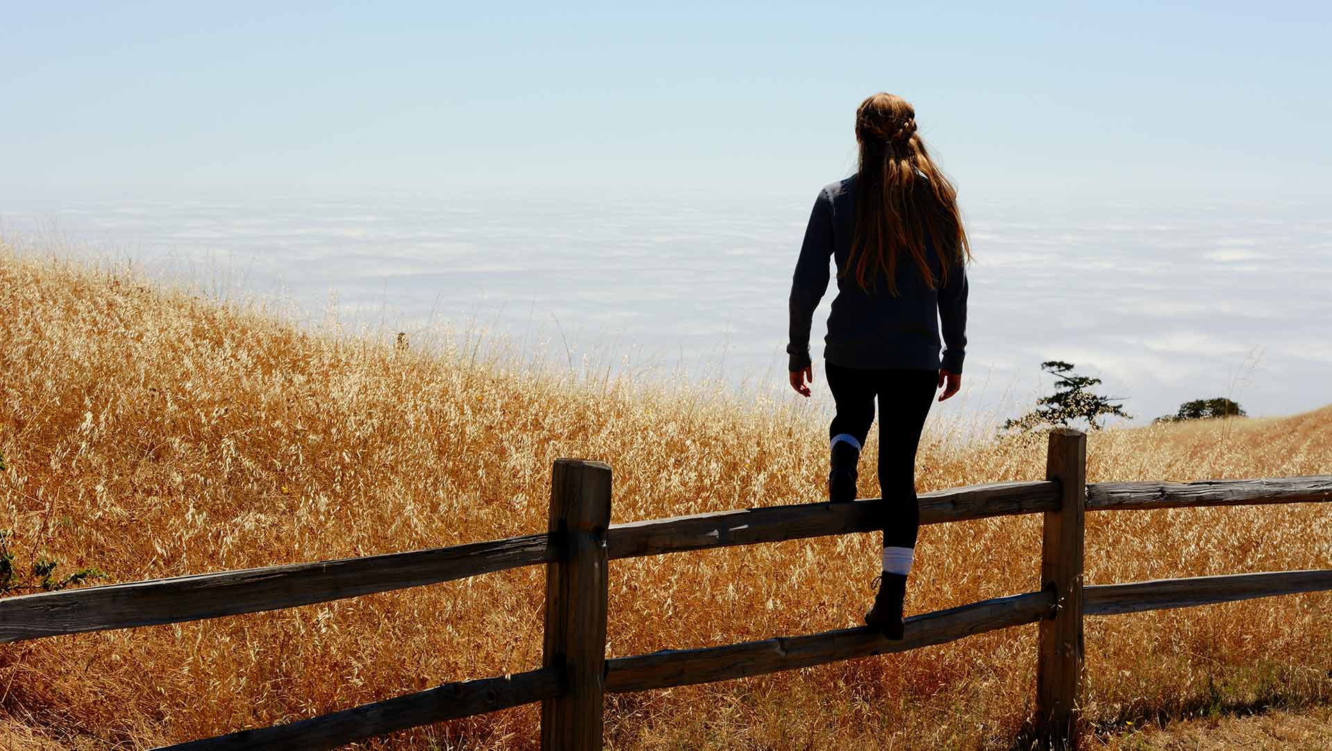 woman standing on fence to overcome trauma